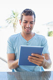 Smiling young man using digital tablet at home