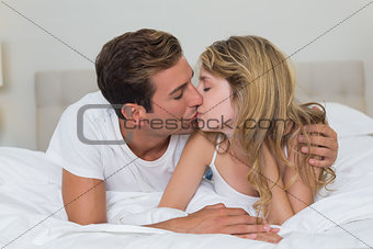 Loving young couple kissing in bed
