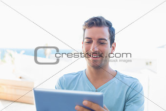 Smiling man using digital tablet at home