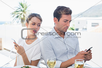 Couple text messaging at food table