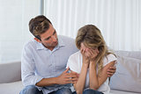 Man consoling a sad woman in living room