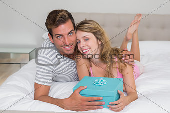 Smiling couple with gift box in bed