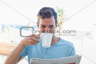 Man drinking coffee and reading newspaper