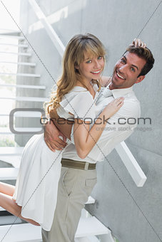 Loving young man carrying woman at home