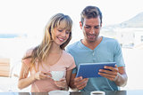 Couple using digital tablet while having coffee