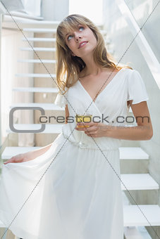 Thoughtful beautiful woman with wine glass on stairs