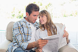 Loving happy couple reading newspaper on couch