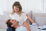 Young man resting on womans lap on couch