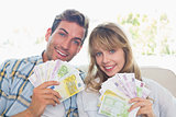 Portrait of a young couple holding fanned out Euro notes