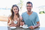 Happy young couple having coffee at table