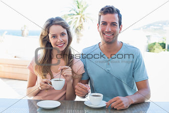 Happy young couple having coffee at table