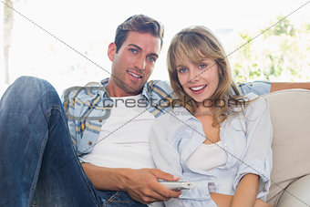 Young couple watching tv on sofa in living room