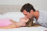 Loving man kissing young woman in bed