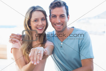 Happy woman showing engagement ring besides man
