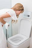 Woman with stomach sickness about to vomit into toilet