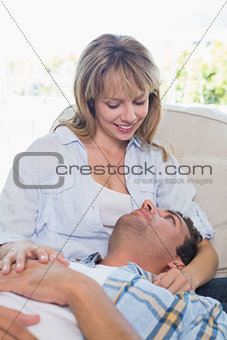 Man resting on happy womans lap on couch