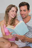 Relaxed young couple reading book in bed