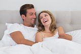 Cheerful relaxed couple sitting in bed