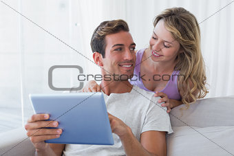Couple using digital tablet together at home