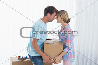 Young couple carrying cardboard box in new house