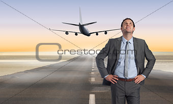 Composite image of smiling businessman with hand on hip