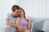 Young couple using laptop on couch
