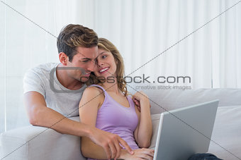 Young couple using laptop on couch