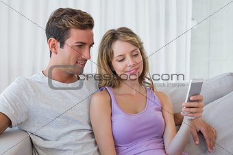 Relaxed couple text messaging on couch