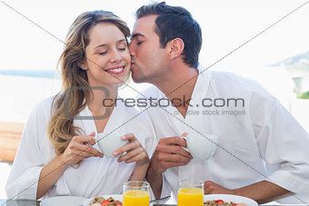 Man kissing woman at breakfast table