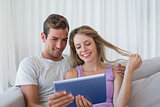 Relaxed couple using digital tablet on couch