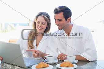 Couple using laptop on breakfast table