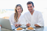 Couple using laptop on breakfast table