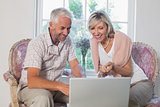 Couple discussing while using laptop at home