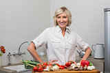 Smiling mature woman with vegetables in kitchen