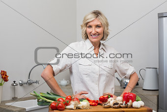 Smiling mature woman with vegetables in kitchen