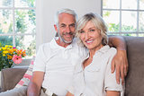 Smiling mature couple sitting on sofa in living room