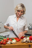 Mature woman chopping vegetables in kitchen