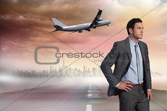 Composite image of businessman with hand on hip
