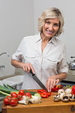 Mature woman chopping vegetables in kitchen