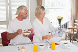 Couple reading newspaper while having breakfast