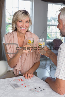 Mature couple toasting drinks while playing cards