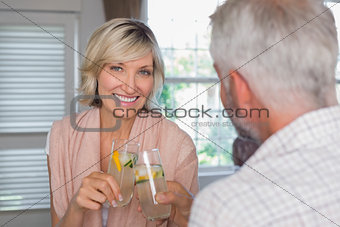 Smiling woman with mature man toasting drinks
