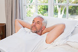 Thoughtful mature man lying in bed