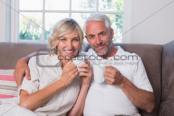 Smiling mature couple with coffee cups in living room