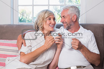 Relaxed mature couple with coffee cups in living room