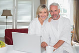 Relaxed mature couple with laptop at home