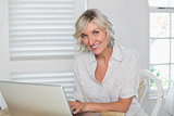 Smiling mature woman using laptop at home