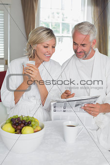 Couple reading newspaper while having breakfast