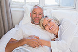 Smiling relaxed mature couple lying in bed