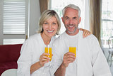 Happy mature couple holding orange juices